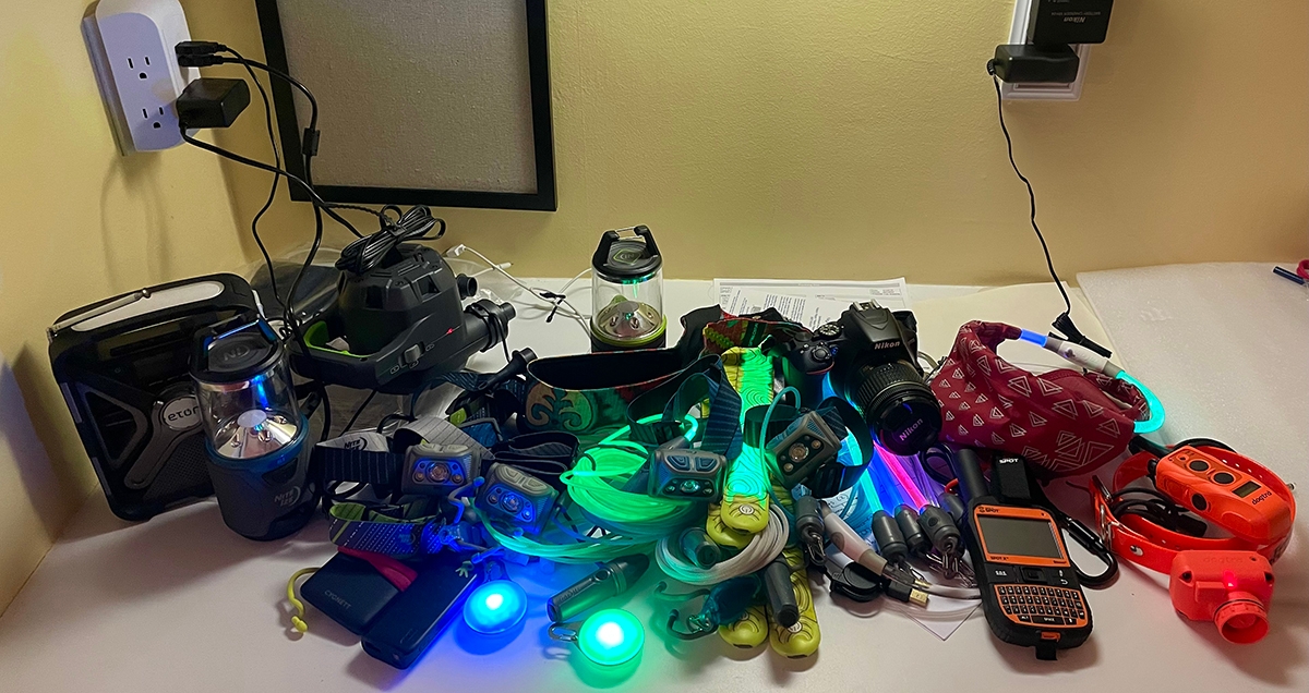 A pile of electronic gear charging. Headlamps, lanterns, external battery packs, gps devices, and light up dog collars and other Nite Ize gear