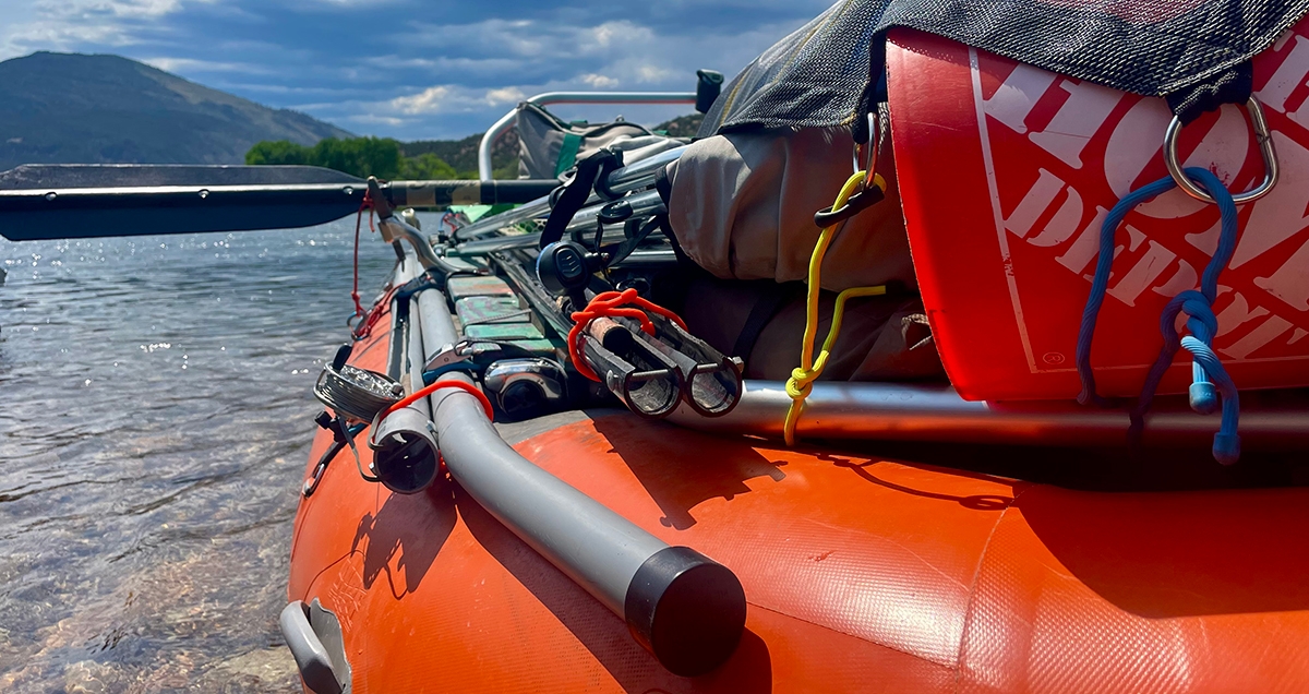 A pack raft on a river bank filled with gear and supplies