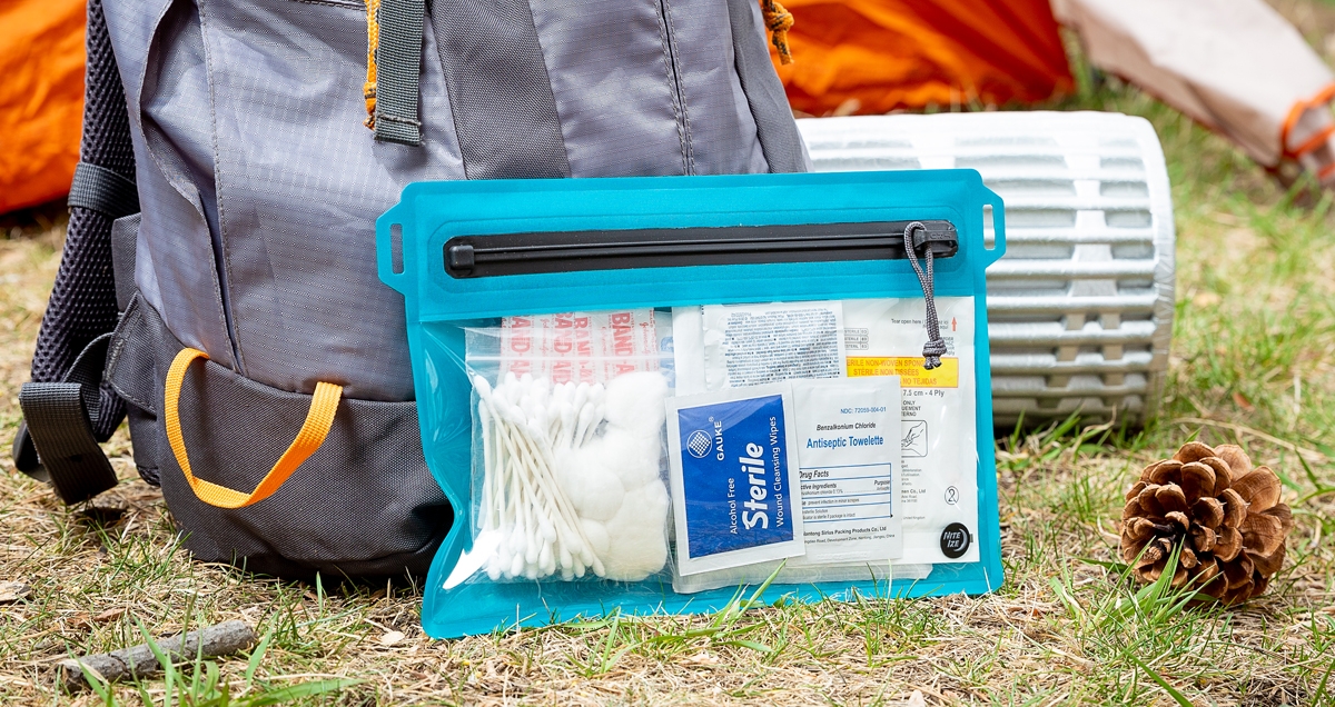 First aid kit packed in a RunOff Waterproof Travel Pouch at a campsite