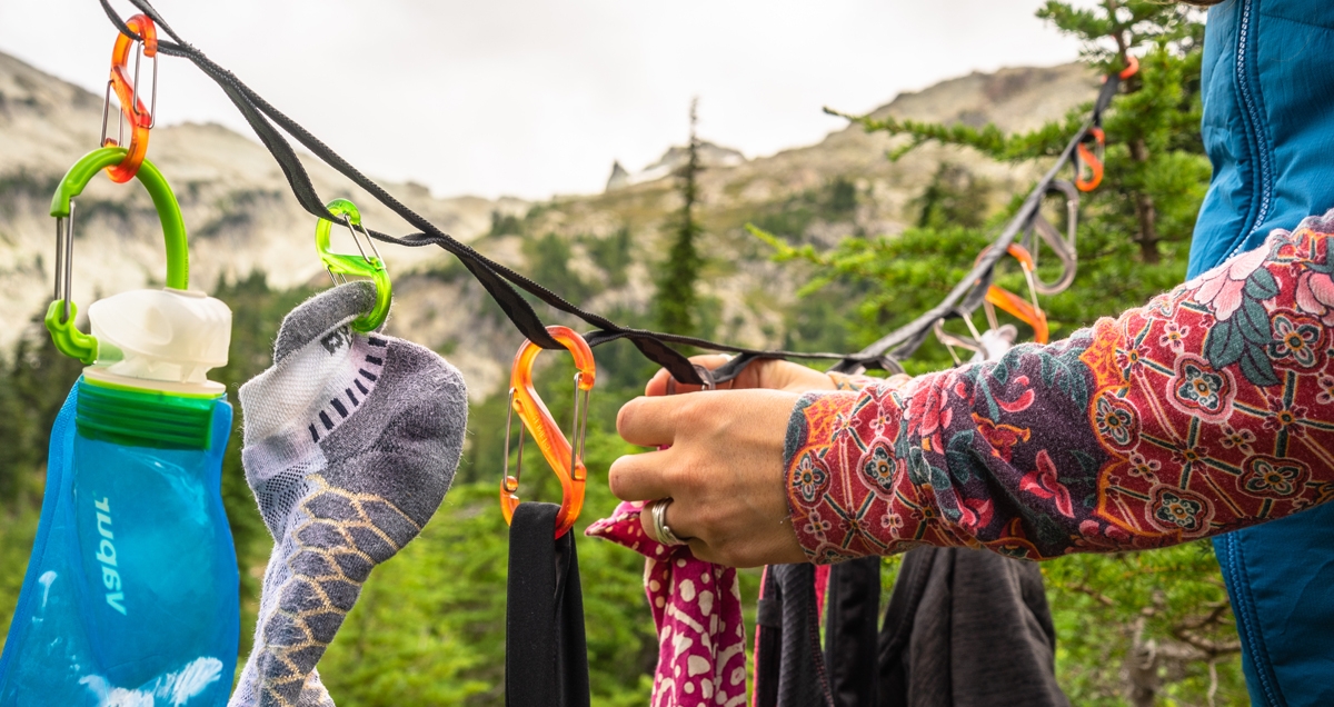 Clothing hanging on a GearLine Organization System attached to two trees at a campsite