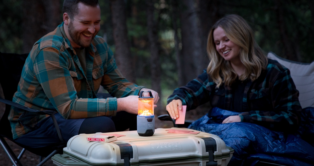 A couple playing cards while camping with a Radiant RL3 Lantern on amber mode