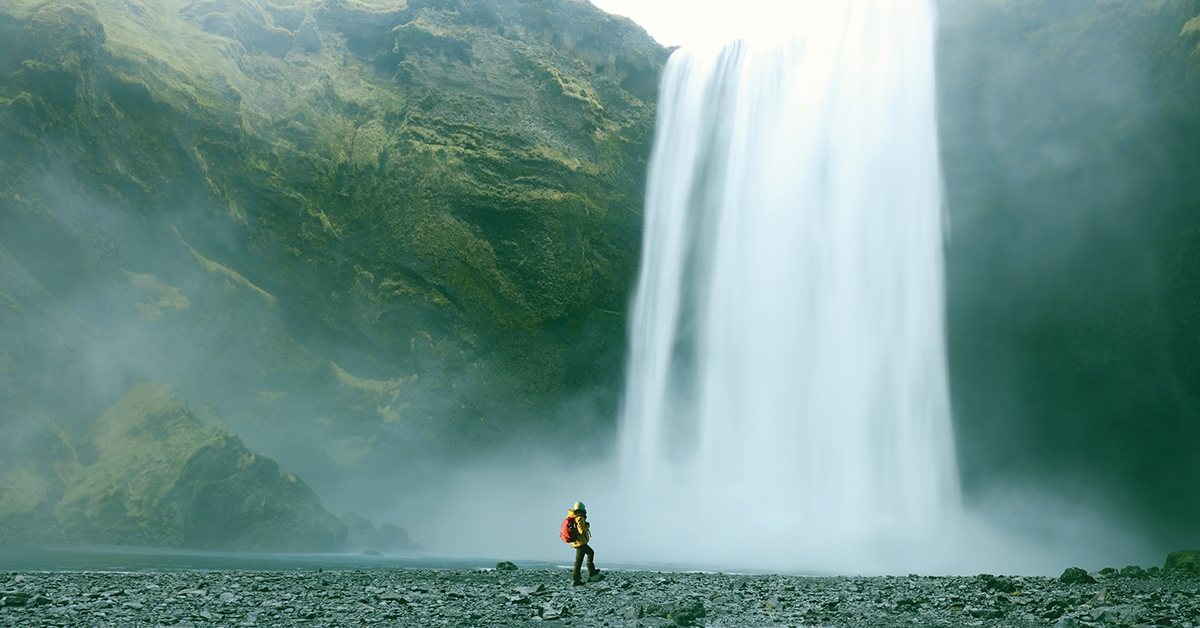 Person hiking next to a waterfall